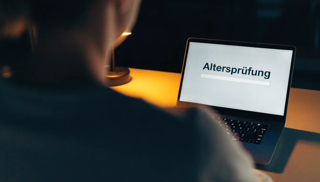 Ein Schreibtisch mit Stehlampe, einem geschlossenen Laptop und einem hölzernen Richterhammer im Halbdunkel.