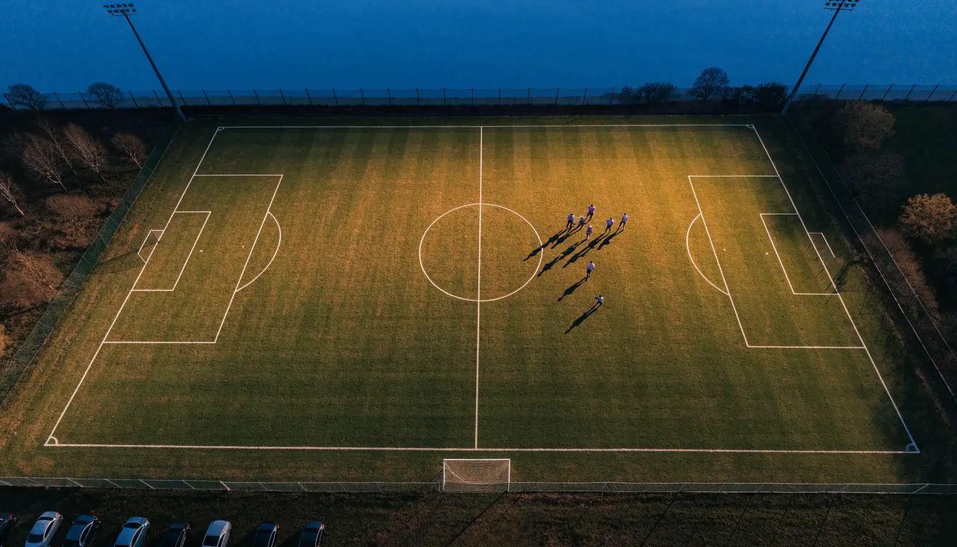 Ein Fußballplatz am Abend aus der Vogelperspektive, Flutlichtmasten ausgeschaltet, die Rasenlinien deutlich sichtbar.